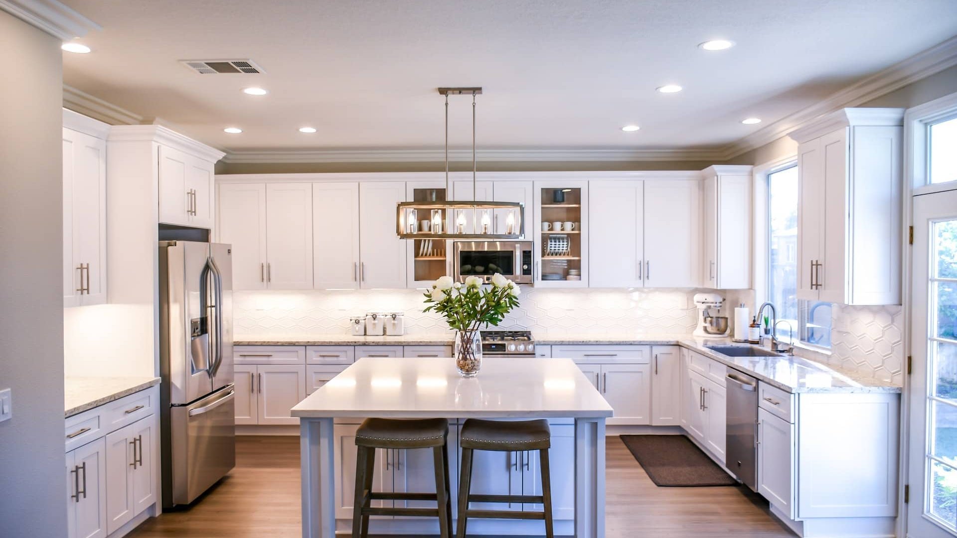 Modern white kitchen renovation with custom cabinetry, granite countertops, and pendant lighting